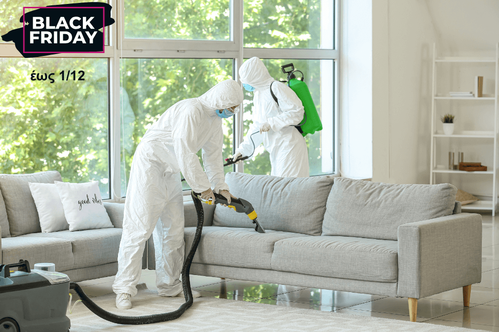 Δύο επαγγελματίες, φορώντας ειδική στολή, καθαρίζουν με ειδικό εργαλείο έναν καναπέ.