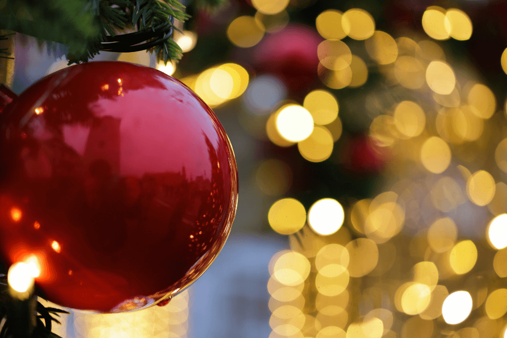 Μιά κόκκινη μπάλα σε χριστουγεννιάτικο δέντρο με φωτάκια.