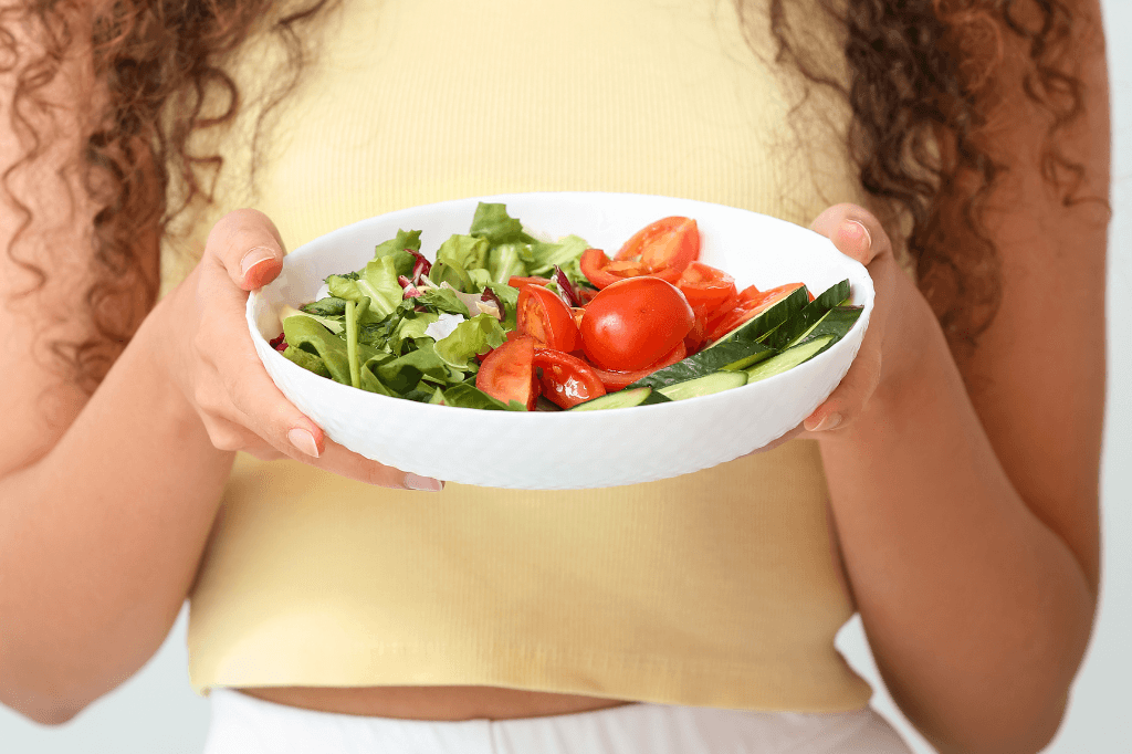 Μια γυναίκα κρατάει ένα πιάτο με σαλάτα λαχανικών