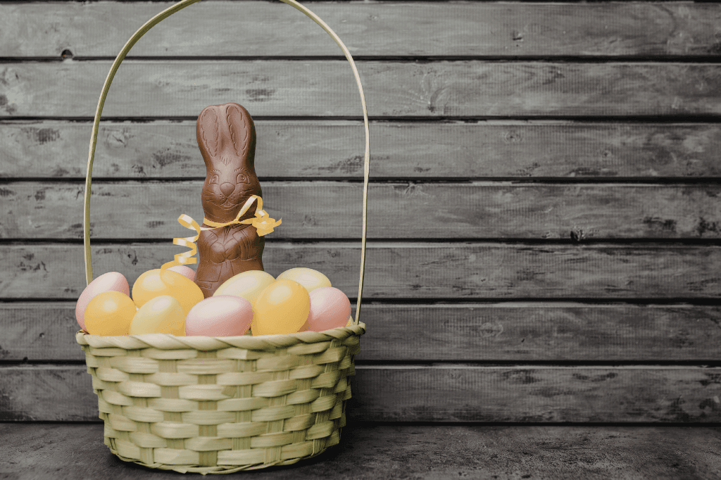 Ροζ και κίτρινα αυγά και οκολατένιο κουνελάκι, μέσα σε ψάθινο καλάθι.