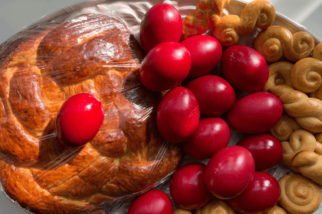 Κόκκινα αυγά με πασχαλινά κουλούρια και τσουρέκι σε πιατέλα.