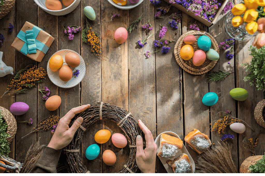 Πολύχρωμα πασχαλινά αυγά επάνω σε τραπέζι με διάφορα είδη διακόσμησης.