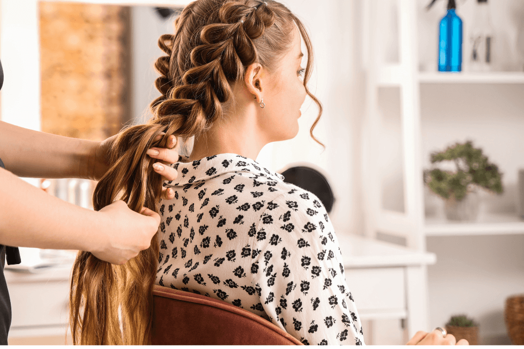 Επαγγελματίας φτιάχνει κοτσίδες σε γυναίκα με μακριά ξανθά μαλλιά.