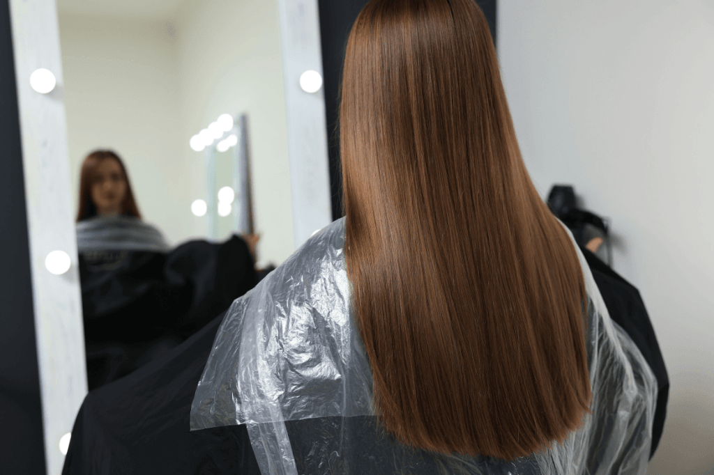 Μια γυναίκα με μακριά ίσια μαλλιά μπροστά σε καθρέφτη.