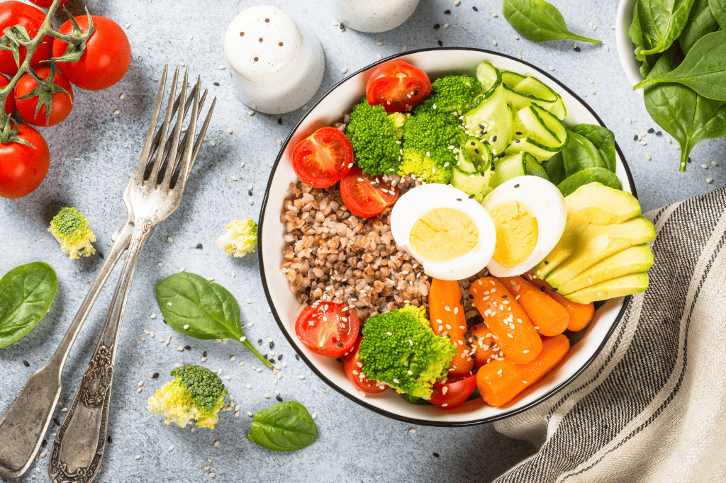 Ένα πιάτο με σαλάτα λαχανικών και αυγά, επάνω σε τραπέζι. Δίπλα μαχαιροπίρουνα και σκόρπια λαχανικά.